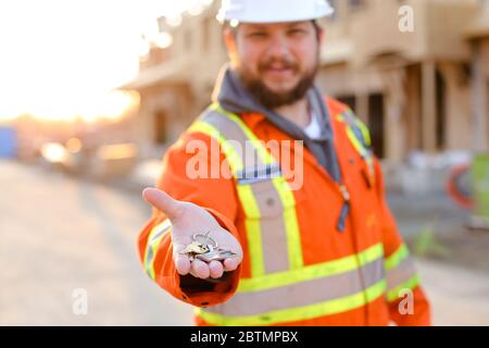 Focus on keys from new house given by foreman in helmet. Stock Photo