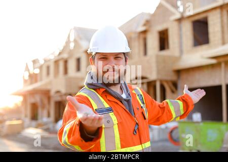Foreman or architect in helmet showing keys from new house. Stock Photo