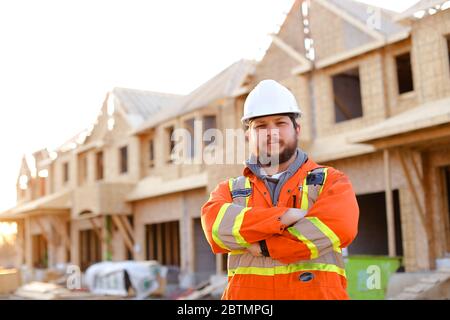 Male foreman standing on construction site with building in background. Stock Photo