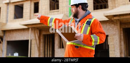 Banner of engineer in orange workwear holding notebook on construction site. Stock Photo