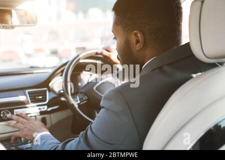 Unrecognizable Driver Man Pushing Buttons Driving Car, Rear View Stock Photo