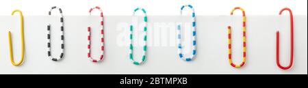 Colored office paper clips on a sheet of paper isolated on white. Stock Photo