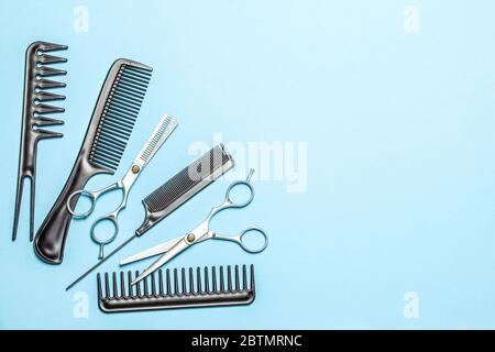 Black combs and combs with scissors on blue background. Copy space for text Stock Photo