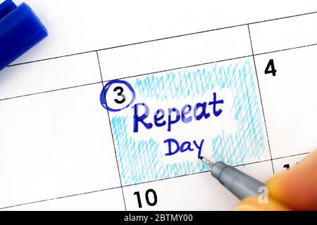 Woman fingers with pen writing reminder Repeat Day in calendar. June 03. Stock Photo