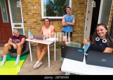 London, UK.Wednesday, May 27, 2020. Housemates (l-r) Leigh, Jessica, Marcus and Holly at their laptops as they work from home on their front drive during the warm weather in Ealing, London. A photo taken as part of a Doorstep Portraits project. Photo: Roger Garfield/Alamy Stock Photo