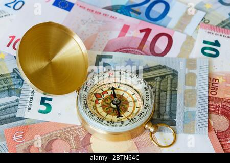 A brass compass on EU money Euro notes banknotes Euros to illustrate direction of the Eurozone economy.  Europe Stock Photo