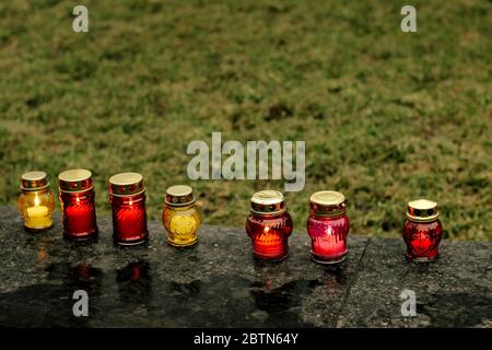 many colorful candles with light burning in city center on marble stone, memorial day and sad bereavement moment Stock Photo