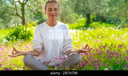 Beautiful calm girl with closed eyes meditating in the fresh blooming garden, unity with nature, zen balance, happy healthy lifestyle Stock Photo