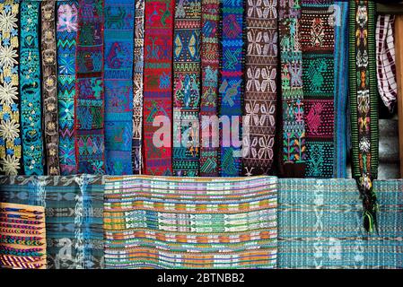 Belts (faja) and multi-coloured handwoven Guatemalan textiles displayed on market stall. Santa Catarina, Lake Atitlán, Guatemala Stock Photo