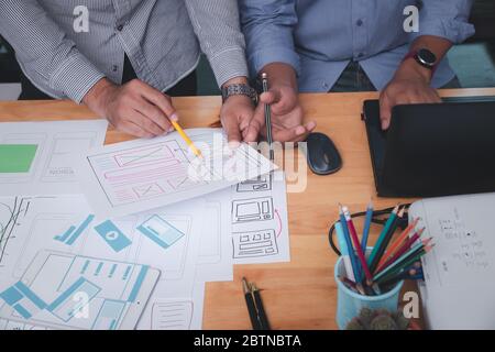 UX or UI designers designing on their smartphone application layout prototype project. Stock Photo
