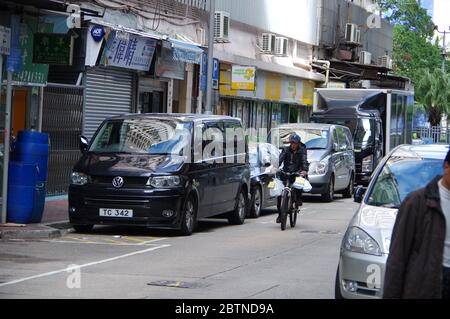 Hong Kong, China - Nov 27, 2016: Middle aged man riding bicycle and VW Transporter MPV parking on the street in Hongkong Stock Photo