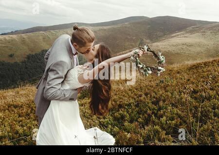 stylish groom  kissing gorgeous bride in sun light, perfect moment, boho wedding couple, luxury ceremony at mountains with amazing view Stock Photo