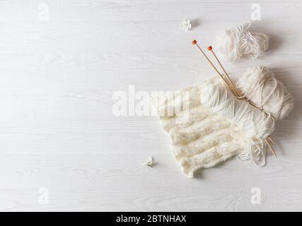 Knitting, knitting needles, yarn and glasses lie on a white wooden background. Flatlay. Stock Photo