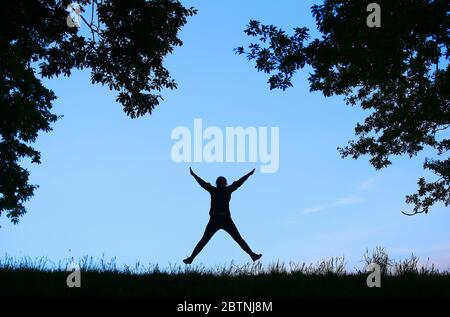 A woman does a star jump in east Belfast, Northern Ireland,  on her daily exercise allowance during the COVID-19 pandemic lockdown. Stock Photo