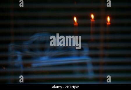 Candles reflected in a window looking onto a garden bench sitting in the back garden of a house in east Belfast, Northern Ireland. Stock Photo