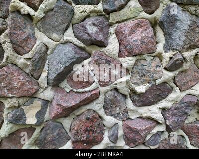 Gray, brown, black stone wall background, granite mosaic stonewall rubble facade closeup texture Stock Photo