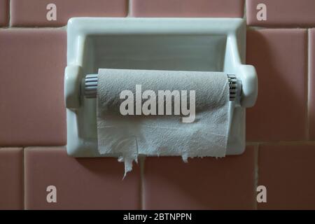 Empty toilet paper roll tube on the wall holder Stock Photo