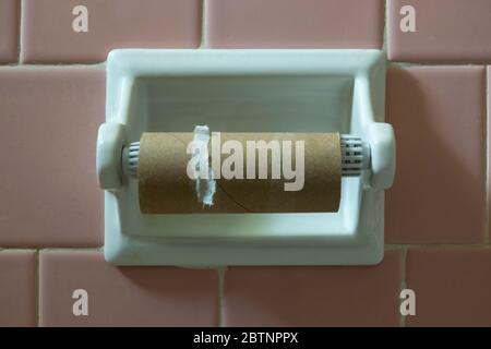 Empty toilet paper roll tube on the wall holder Stock Photo