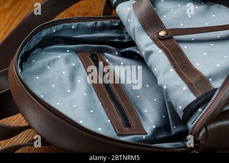 Open empty bag made of handmade genuine leather with elements of locks on a wooden background. Close up Stock Photo