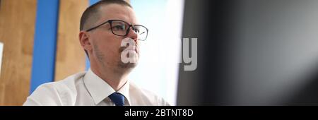 Confident and pensive man working with computer at workplace Stock Photo