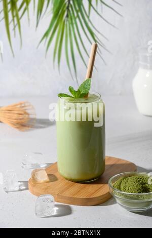 Iced Green matcha latte tea in glass on light white background. Close up.Vertical format. Stock Photo
