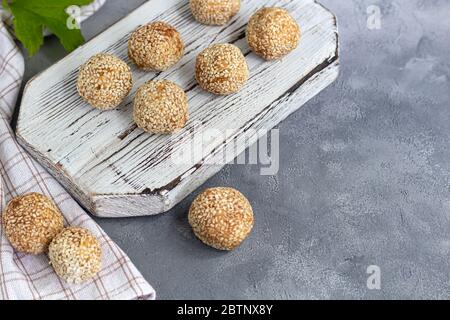 Energy bites without baking are made from ingredients - nuts, cocoa, chocolate, oats and sesame seeds. Located on a gray background. Stock Photo