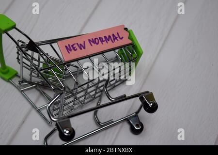 New Normal write on sticky note with mini trolley isolated on wooden table. Stock Photo