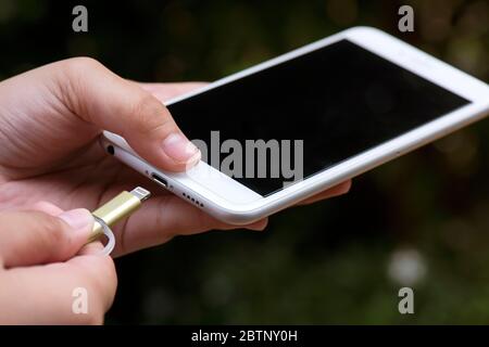 ็Hands plugging a charger in a smart phone on outdoor Stock Photo