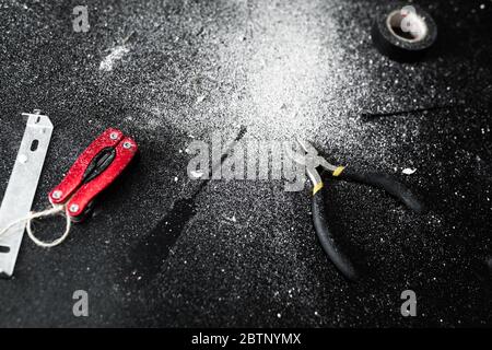 A set of tools for self-installation of the lamp lies on a black table, sprinkled with white dust. Husband for an hour. Household chores Stock Photo