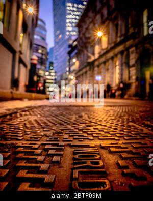 A shallow depth of field shot of a manhole cover with the walkie talkie building in the background. Stock Photo