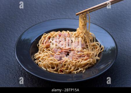 Spaghetti with Spicy Mixed Ham on black plate Stock Photo