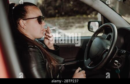 can u smoke cigarettes while driving You Driving?| TicketSniper Young woman smoking a cigarette