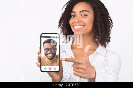 Black girl showing cell phone with male profile on screen Stock Photo