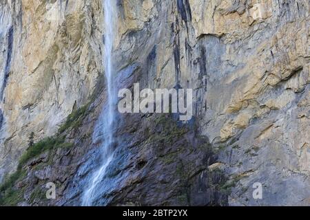 Falling waters of the Staubbach waterfall are visible on the background of the rock walls. This is located in Lauterbrunnen, Switzerland. Stock Photo