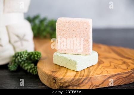 Pink foaming bath bomb cube on wooden tray with towels and succulents  ready to be used for a relaxing spa experience Stock Photo