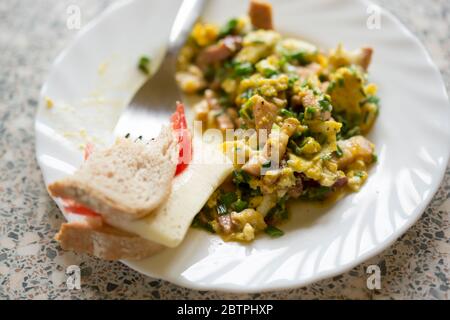 Scrambled eggs with bacon, ham, chives with sandwich cheese and tomato Stock Photo