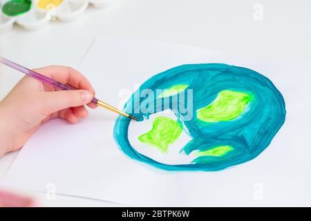 Child draws planet for earth day. Protection of environment. Earth Day celebration. Save world and unity concept. Stock Photo