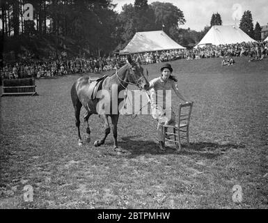 Staking Her Claim ! Photo Shows : Leading her poney , a girl rider eagerly lays claim to a chair as the music ceases during the Musical Chairs competition - one of the many mounted events at the Haywards Heath Horticultural Society ' s summer show in Victoria Park , Haywards Heath , Sussex . 9 Jul 1936 Stock Photo