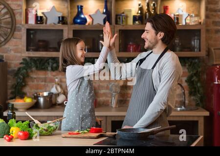 Happy Little Girl Giving High Five To Father After Preparing Lunch Together Stock Photo