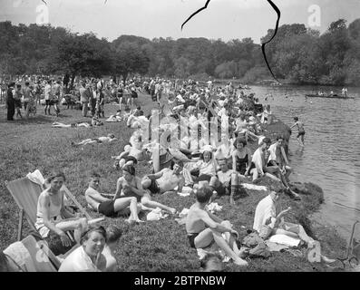 Sunny Sunday by the Thames. The hot sun induced thousands of people to spend Sunday, unhampered by weekday clothing, on the shady banks of the Thames. Photo shows: sunbathers crowding the river bank at Runnymede. 6 June 1937 Stock Photo