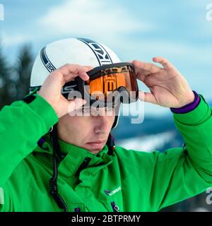 A man skier wearing a helmet briko and ski goggles swans before training for safety. A professional snowboarder prepares for competitions 2021. Yablun