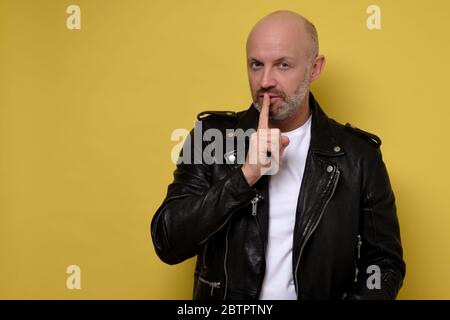 Serious italian man keeps fore finger on lips, tries to keep conspiracy. Stock Photo