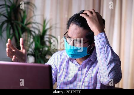 Sad man in face mask working on laptop  Stock Photo