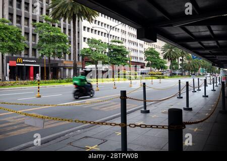 Makati, Manila, Philippines - May, 26, 2020: Empty Ayala avenue with delivery motorcycle biker moving fast. Coronavirus covid quarantine concept Stock Photo