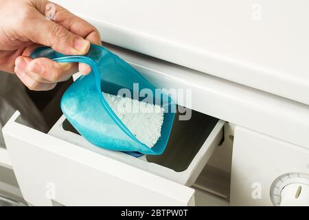 Man putting laundry detergent powder in a washing machine
