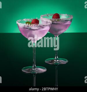 Two tall cocktail glasses with pink gin and tonic garnished with large  crystals of salt on an edge of a glass, large piece of ice, peppermint  Stock Photo - Alamy