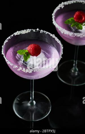 Two tall cocktail glasses with pink gin and tonic garnished with large  crystals of salt on an edge of a glass, large piece of ice, peppermint  Stock Photo - Alamy