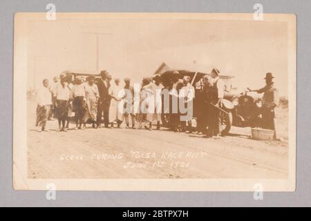 Scene from Tulsa Race Riot June 1st 1921. This black-and-white photographic postcard, titled Scene from Tulsa Race Riot June 1st 1921 depicts a group of men and women standing along the side of the road in front of two cars. The men to the right of the image are armed. Stock Photo