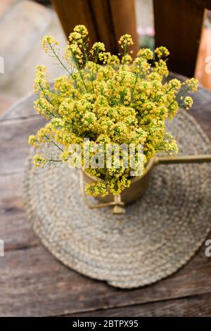Beautiful yellow wild flowers on the wooden table in the backyard Stock Photo