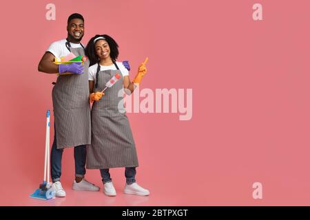 Cleaning Service Ad. Black Couple With Household Supplies Pointing At Copy Space Stock Photo